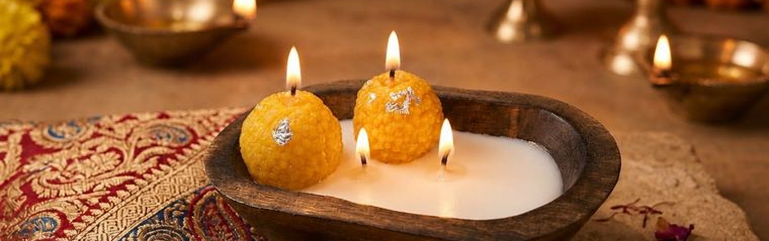 Lit laddoo candles with silver vark in the Maumm workshop